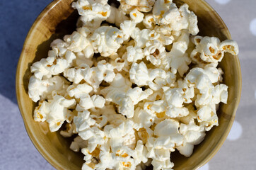 Popcorn in a brown plate close-up. Snack for watching movies.