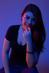 Portrait beauty young asian woman in the dark studio room of color of blue and red or mixed color, colors lights with smiley face. Attractive Asia girl has long hair. pretty lady happy fashion concept