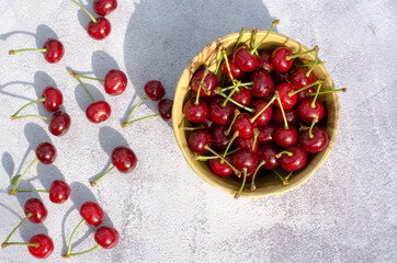 Ripe juicy cherry in a brown plate and on the table. Gardening concept.
