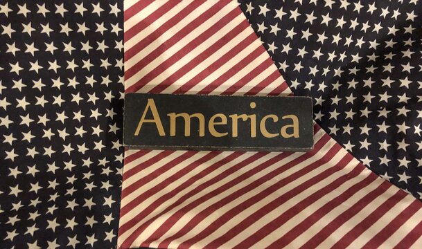Wooden American sign on top of several red, white and blue colored flags