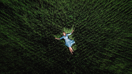 girl in a blue dress in a field of wheat. top view