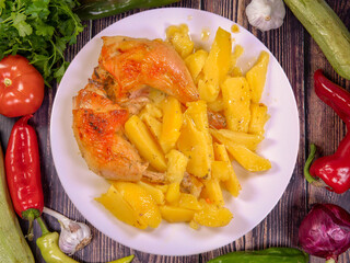 Delicious roasted chicken legs with boiled potatoes on a white plate. Top view