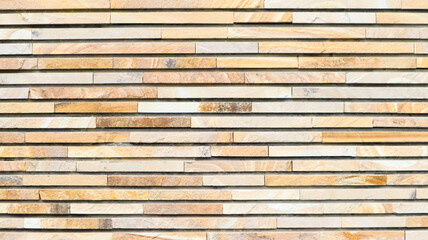 Decorative texture of a beautiful wall with rectangular parts made of multi-colored artificial stone. Collage of narrow granite blocks. Exterior finish with stone. Background from natural material.