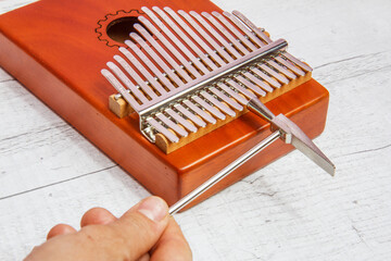 17-key Kalimba, ethnic plucked musical instrument.  A hand with a hammer  tuning this mbira.