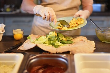 woman fills and rolls a vegetable wrap