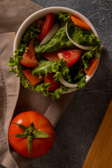 Tomatoes in salad inside a white bowl on grayish background