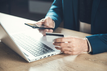 Obraz premium man hand credit card with phone and computer