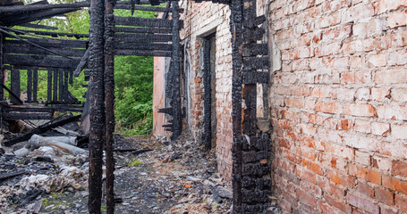 The burned-out house and furniture. Charred remains of a house after a fire with a brick wall.