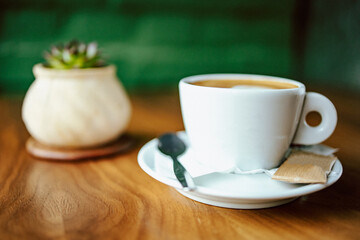 Fresh cappuccino on the table in white cup with plant decoration. Coffee break
