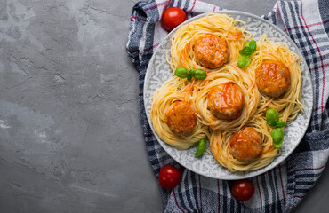 Pasta with meatballs in tomato sauce. View from above. Gray background. Free space.