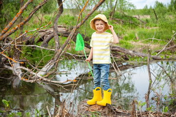 European cute boy in Panama stands with a net in a pond, swamp. He is going to catch the inhabitants of the reservoir. Environmental education of children, nature research, young naturalist.