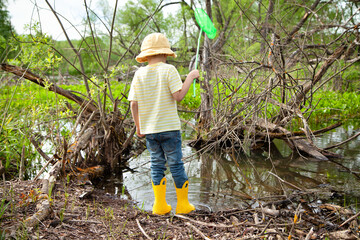 European cute boy in Panama stands with a net in a pond, swamp. He is going to catch the...