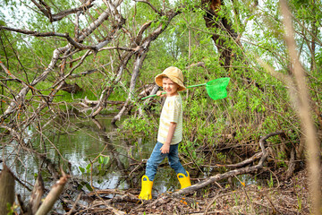 European cute boy in Panama stands with a net in a pond, swamp. He is going to catch the...