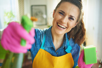 smiling woman with cleaning agent and sponge housecleaning