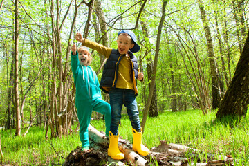Two boy friends represent strong men in the spring forest. Friends since childhood, family vacation in the forest. Happy family. A family with two children.