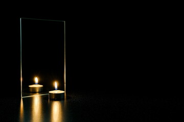 burning candle and mirror on a black background. reflection of a candle flame in a mirror in the dark