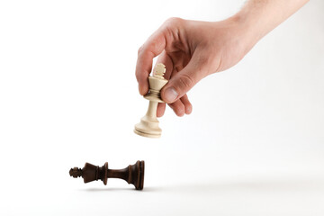 hand holds a chess king piece and defeats another king