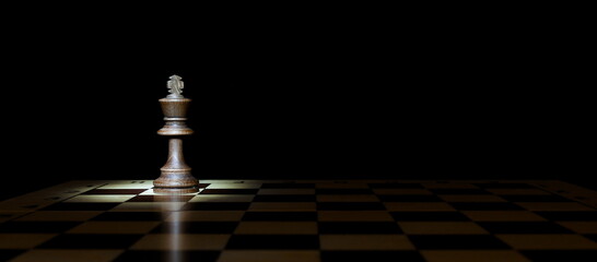 king figure on a chessboard with spotlight in the dark with copy space
