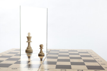 reassessment of their abilities. the pawn is reflected in the mirror like a king on white background