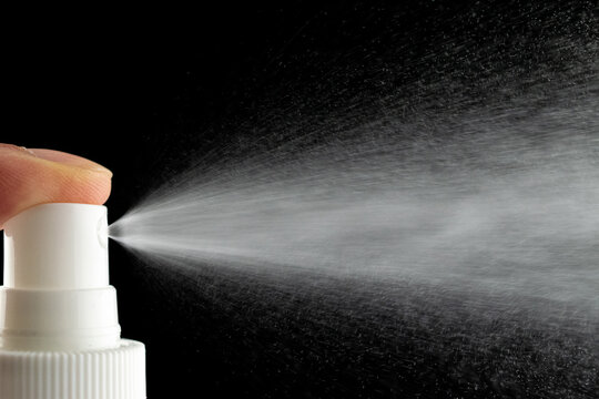 Mist spray aerosol bottle for perfume isolated on black. Splash water liquid background.