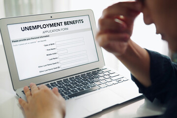 Unemployed depressed person filling out an online unemployment benefits application form using...