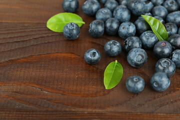 blueberry berries with green leaves on dark wooden background top view with copy space