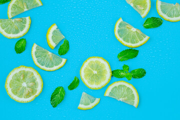 Frame from lemon slices and mint leaves on blue pastel table top view. Ingredients for summer drink and lemonade. Flat lay style