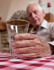 Old man holding glass of water