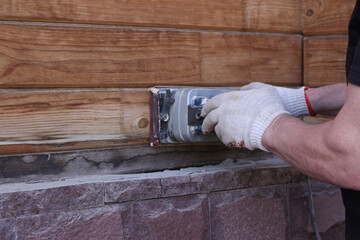 Gloved carpenter uses wood polisher. Cleaning and polishing of wooden surfaces. A man makes repairs at home