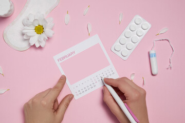 menstrual sanitary tampon, pad, pain pills and white chamomile flower on pink background, feminine calendar with copy space. Care of hygiene during menstruation. top view. mock up