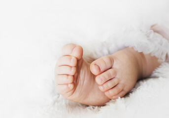 Newborn baby feet are wearing a lace skirt