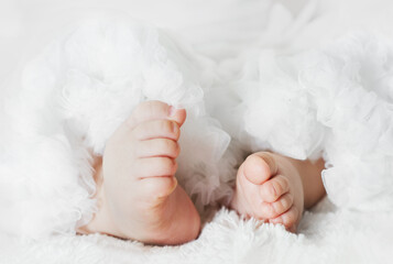 Newborn baby feet are wearing a lace skirt