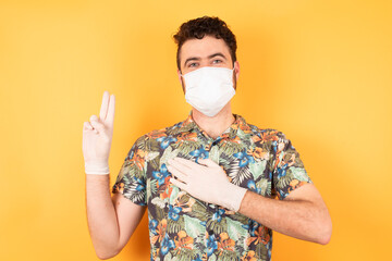 Young handsome caucasian man with short hair wearing casual hawaiian shirt and medical mask smiling...