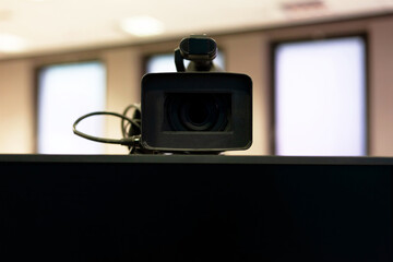 Professional modern video camera above a blank monitor screen closeup, frontal shot. Streaming...