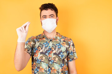 Handsome young businessman wearing hawaiian shirt and medical mask pointing up with hand showing up seven fingers gesture in Chinese sign language QÄ«.