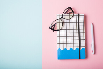 Notebook, glasses and a pen on color background. Flat lay.