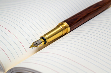 Gilt pen rests on open notebook for notes or writing a text