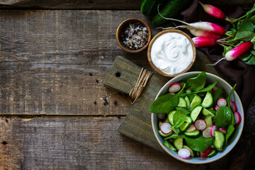 Obraz na płótnie Canvas Healthy vegan food. Vegetarian vegetable salad of spinach, radish and fresh cucumber. Top view flat lay background. Copy space.