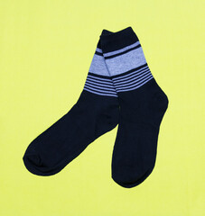 A pair of black men's socks on a yellow background