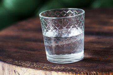 An authentic glass of drinking water on the old wooden table. Full-time atmospheric lighting, fashionable trendy spot soft focus. Preparation for creative design.