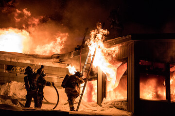 Huge fire blazing in commercial building and firefighter on a roof in winter condition.