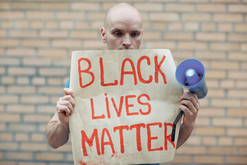 white protesting man holds in his hands a poster with the inscription black lives matter