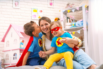 Happy family. A laughing young woman plays superhero games with her children.