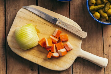 Ingredients for a pasta salad on an old wooden table, tomatoes, olives, pickles, crab sticks, onion...