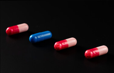 Multicolored capsules with medicine on a black background