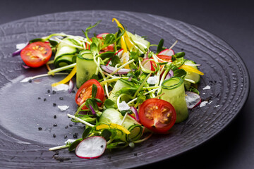 Authentic fresh vegetable salad with sprouts and peas black pepper on a black plate. Morning atmospheric lighting, fashionable trendy spot soft focus. Preparation for design creative menu.