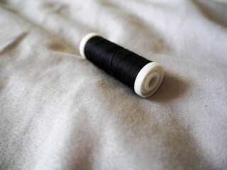 Fototapeta na wymiar a plastic skein of black silk threads on a gray cotton fabric. hobby sewing
