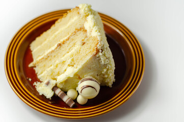 A piece of layered white cream cake with confectionery decorations