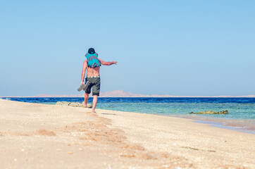 Barefoot man walks along the sandy sea coast
