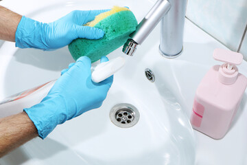 A woman is cleaning a sink in the bathroom. Coronavirus toilet room disinfection.